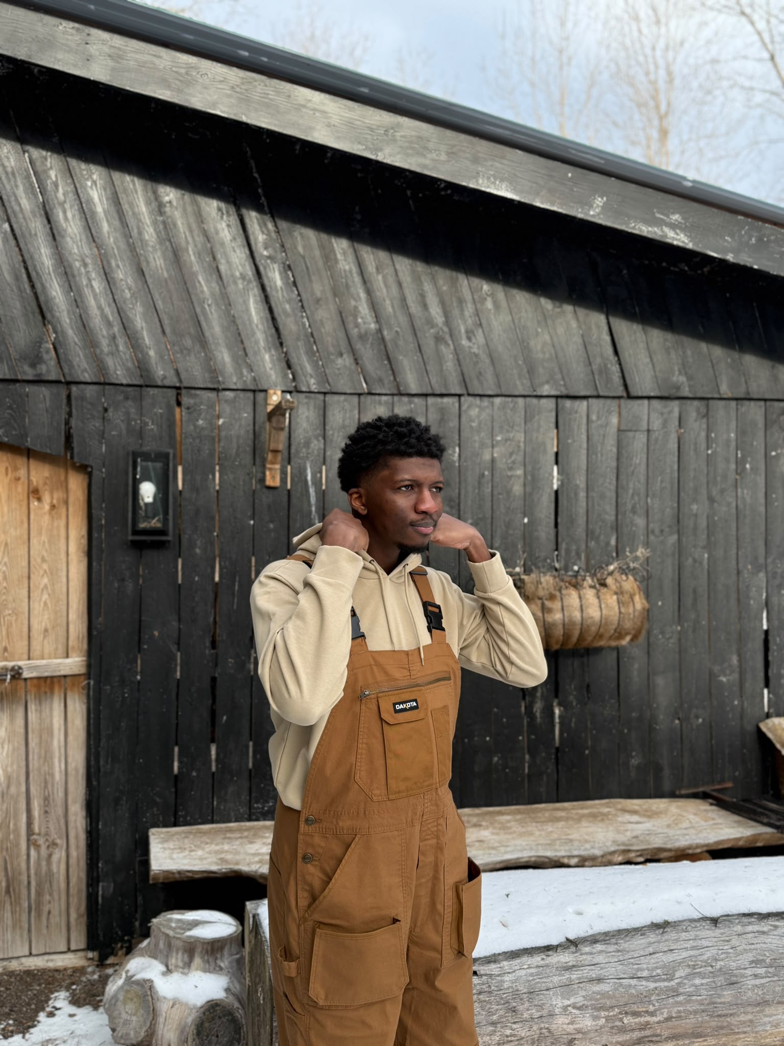 Joshua outdoors beside a wooden cabin in winter